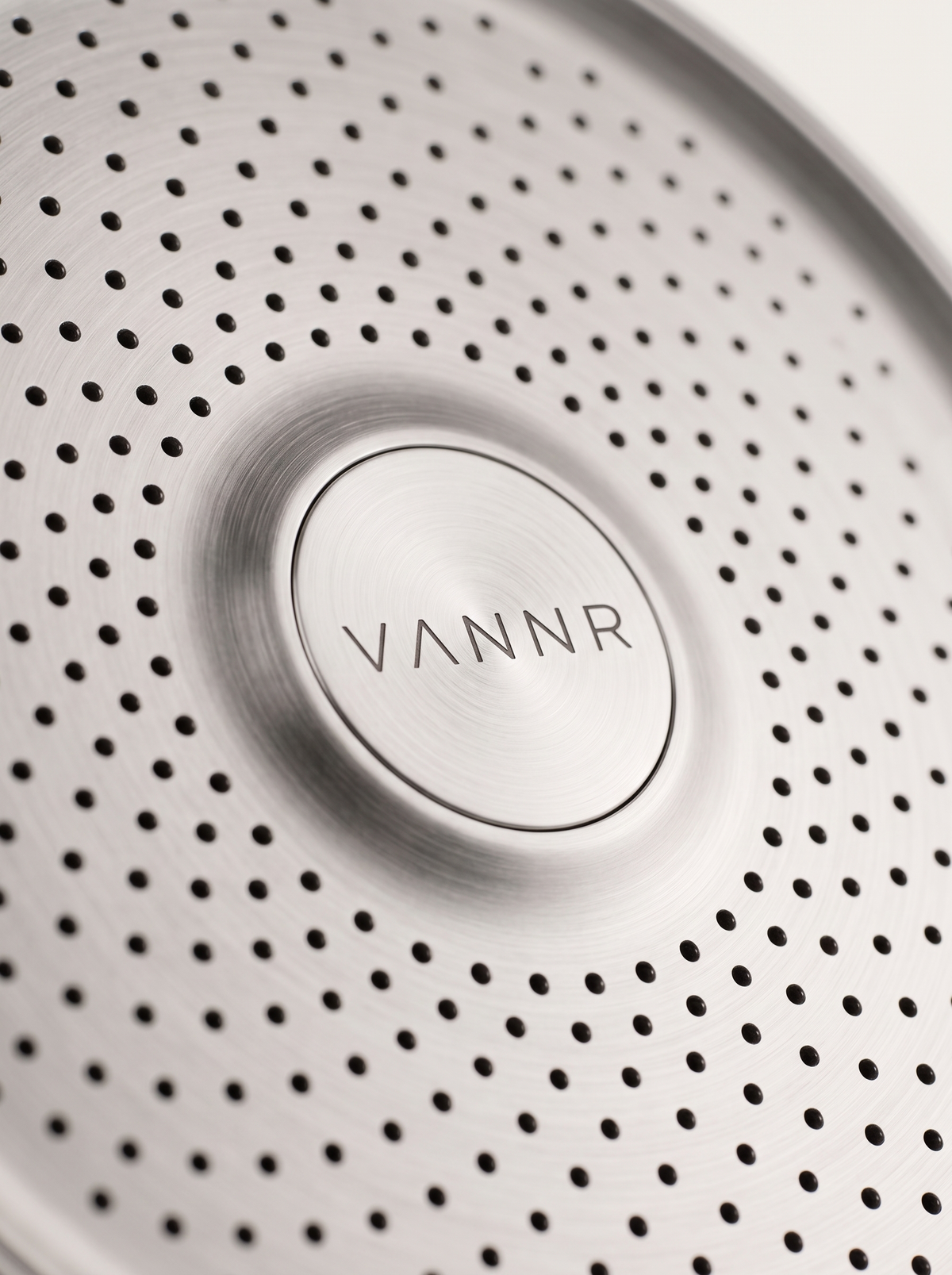 Macro detail of the perforated spray face and the etched VANNR wordmark.