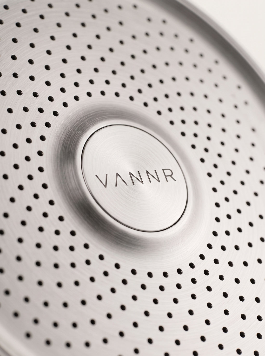 Macro detail of the perforated spray face and the etched VANNR wordmark.