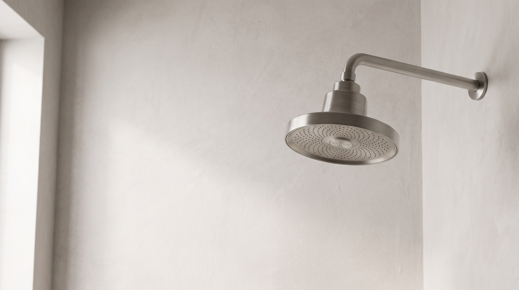 Concept visual of the VANNR ONE filtered showerhead installed on a shower arm in a plaster-walled bathroom.